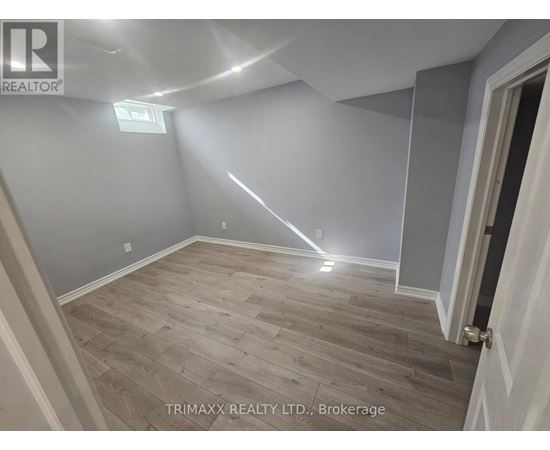 A room with wooden flooring and a door on the right side.