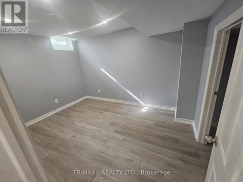 A room with wooden flooring and a door on the right side.