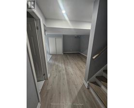 A hallway with wood flooring and a staircase on the right.