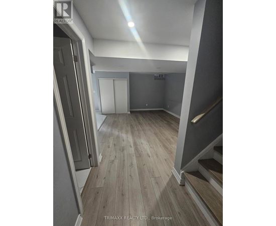 A hallway with wood flooring and a staircase on the right.