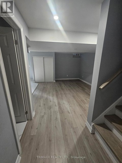 A hallway with wood flooring and a staircase on the right.