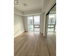 A room with wooden flooring and sliding glass doors leading to a balcony.