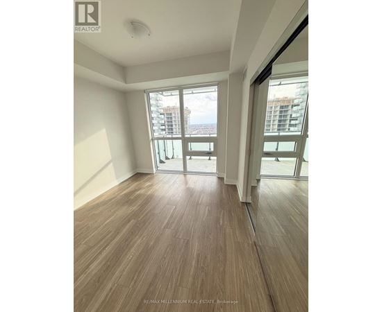 A room with wooden flooring and sliding glass doors leading to a balcony.
