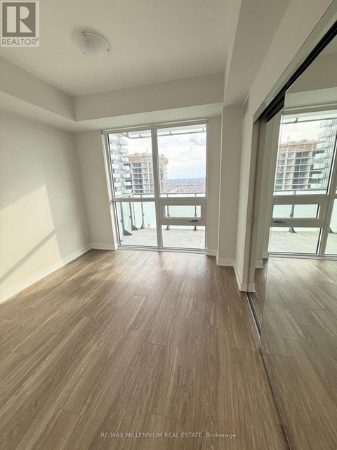 A room with wooden flooring and sliding glass doors leading to a balcony.