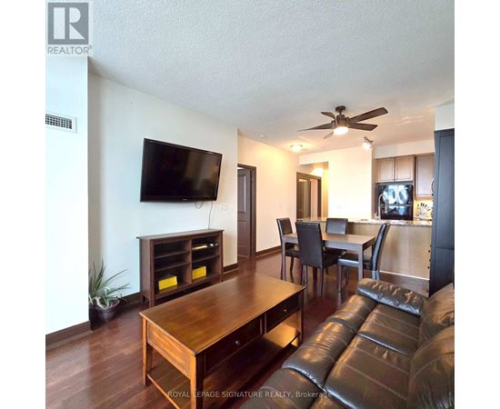 A living room with a brown leather couch and a wooden table.