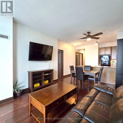 A living room with a brown leather couch and a wooden table.