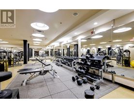 A gym with a variety of equipment including dumbbells, benches, and weight machines.