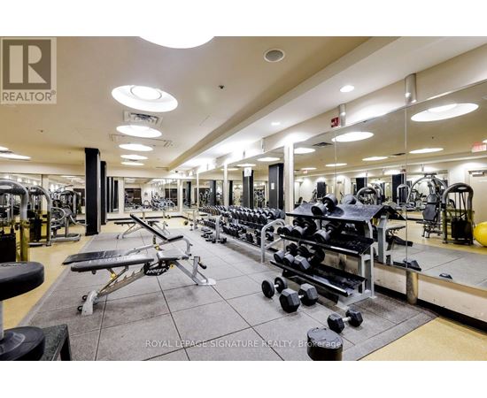 A gym with a variety of equipment including dumbbells, benches, and weight machines.