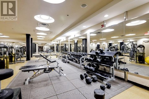 A gym with a variety of equipment including dumbbells, benches, and weight machines.