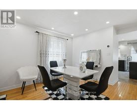 A dining room with a white table and black chairs.