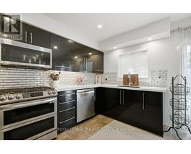 A modern kitchen with black cabinets and a white brick backsplash.