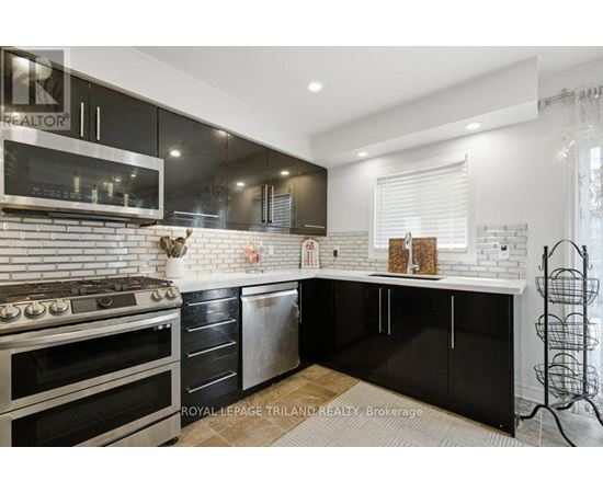 A modern kitchen with black cabinets and a white brick backsplash.