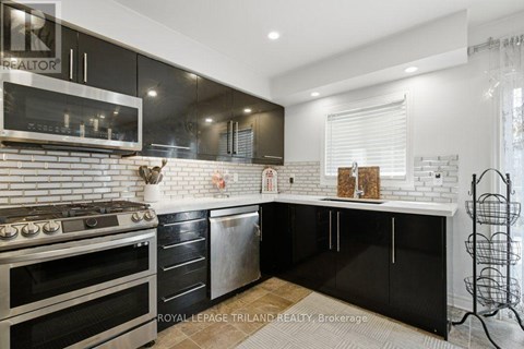 A modern kitchen with black cabinets and a white brick backsplash.