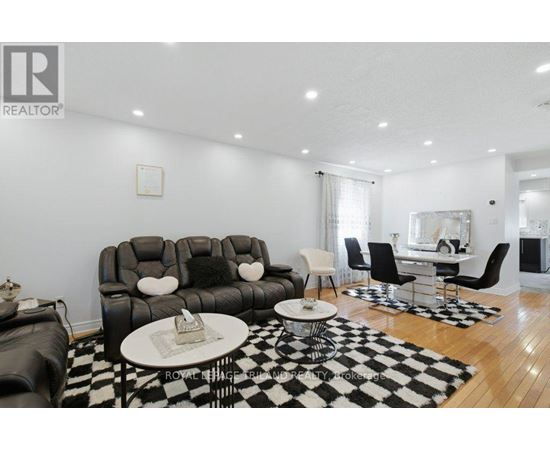 A living room with a black and white checkered rug and a black leather couch.