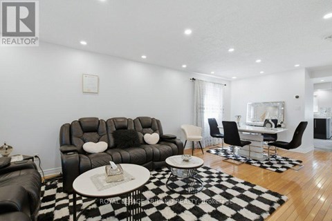 A living room with a black and white checkered rug and a black leather couch.