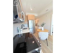 A modern kitchen with a black countertop and a small table with a plant on it.