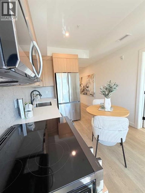 A modern kitchen with a black countertop and a small table with a plant on it.