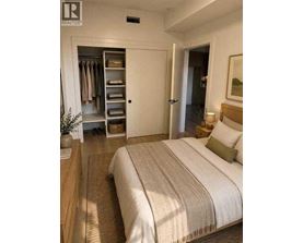 A bedroom with a large bed and a wardrobe with open doors.