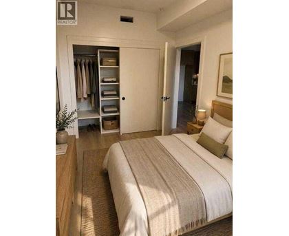A bedroom with a large bed and a wardrobe with open doors.