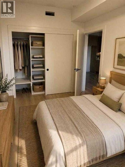 A bedroom with a large bed and a wardrobe with open doors.