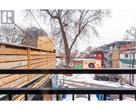 A view from a balcony overlooking a snowy street with buildings and a car.