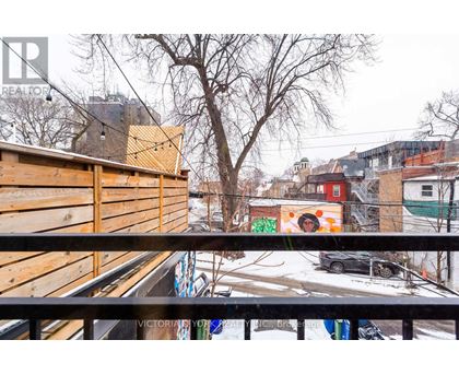 A view from a balcony overlooking a snowy street with buildings and a car.