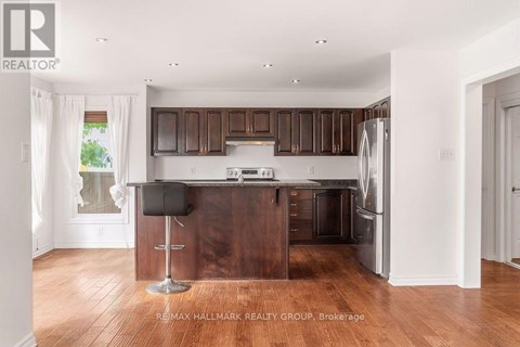 A kitchen with brown cabinets and a black bar stool.