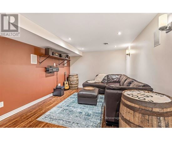 A living room with a leather couch and a guitar on the wall.