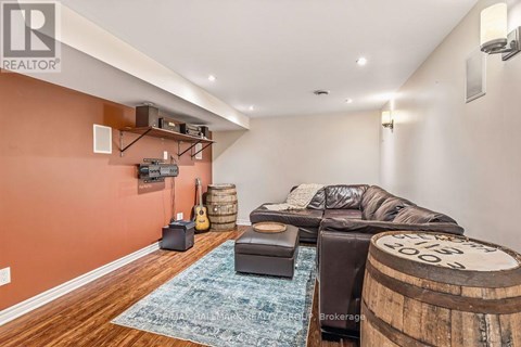 A living room with a leather couch and a guitar on the wall.