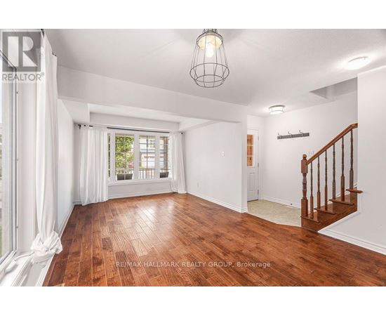 A spacious room with wooden floors and a staircase.