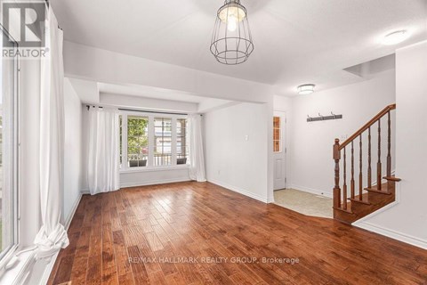 A spacious room with wooden floors and a staircase.