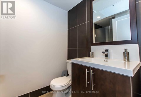 A bathroom with a toilet, sink and mirror.