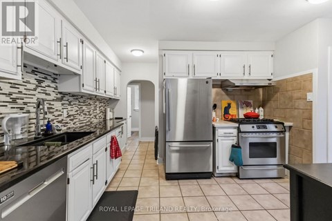 A kitchen with white cabinets and a stone backsplash.