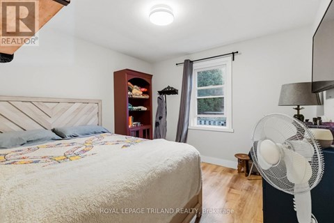 A bedroom with a bed, a fan, and a window with a view of trees.