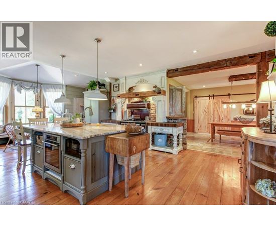 A large, open-plan kitchen and living room with wooden floors and a mix of modern and rustic furniture.