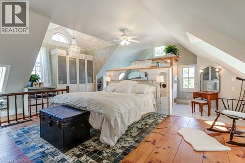 A bedroom with a large bed and a ceiling fan.