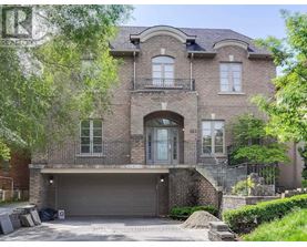 A large, two-story house with a garage is surrounded by greenery.