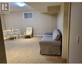A living room with a couch, chairs, and a dining table.