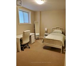 A bedroom with a bed, desk, and chair.