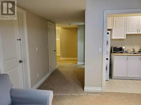 A living room with a grey couch and a kitchen area in the background.