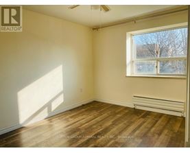 A room with wooden flooring and a window letting in sunlight.