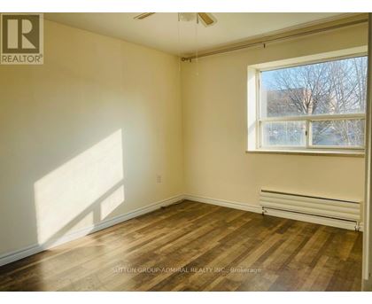 A room with wooden flooring and a window letting in sunlight.