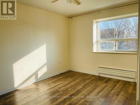 A room with wooden flooring and a window letting in sunlight.