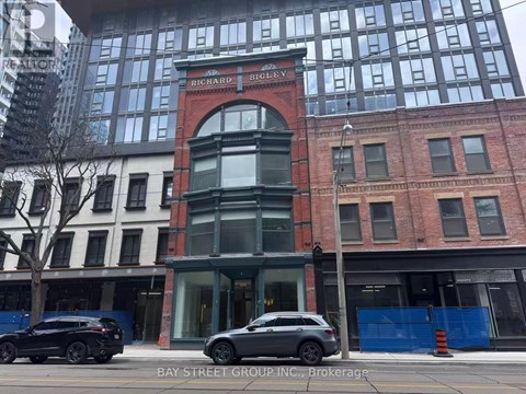 A car is parked in front of a building with a sign that says "Bay Street Group Inc.".