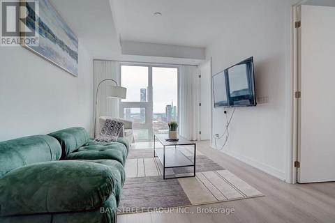A living room with a green velvet sofa and a television on the wall.