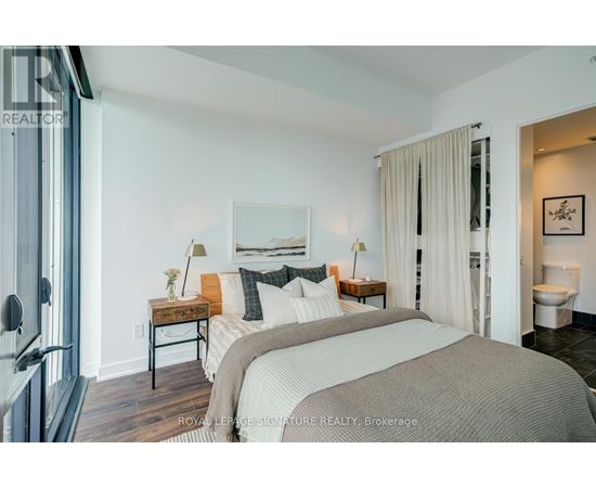 A bedroom with a large bed and a painting on the wall.