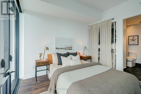 A bedroom with a large bed and a painting on the wall.
