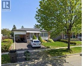 A white car is parked in front of a house with a tree to the right.