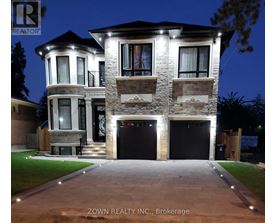 A house with a stone facade and a large front yard is illuminated at night.