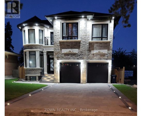 A house with a stone facade and a large front yard is illuminated at night.